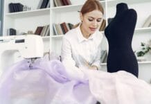 Krawcowa pracuje z tkaniną przy manekinie i maszynie do szycia